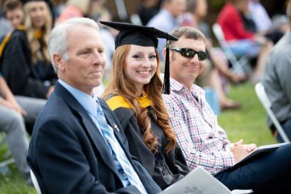 A graduate sits with family. 