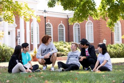 Students sitting on the grass talking outside Lancaster Hall