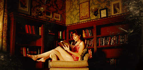 Woman reads while books pile up behind her GIF