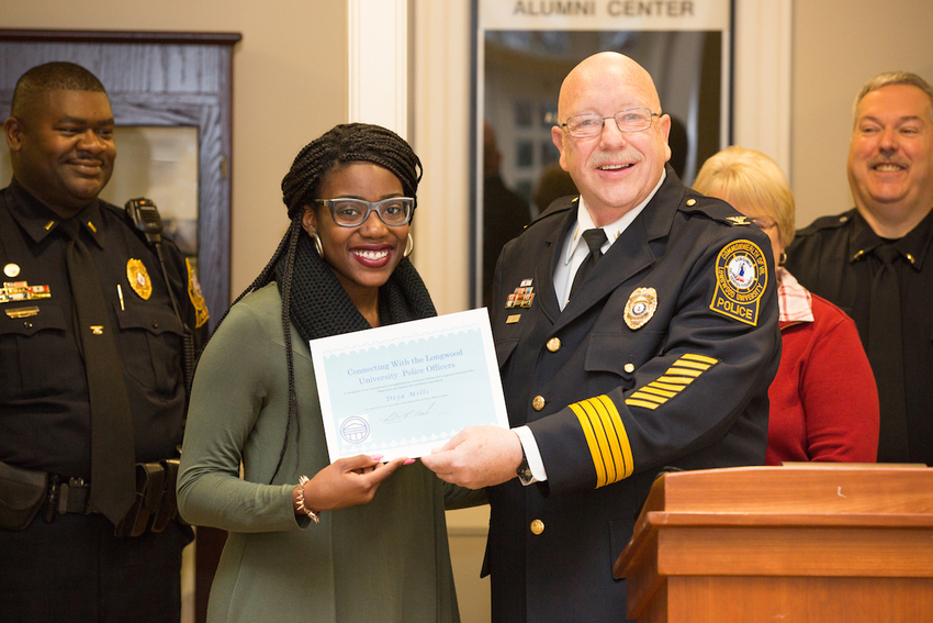 Deja Mills '17 is named winner of Selfies with the Longwood Police by Chief Bob Beach. Behind are Lt. John Johnson (left) and Lt. Ray Ostrander (right)